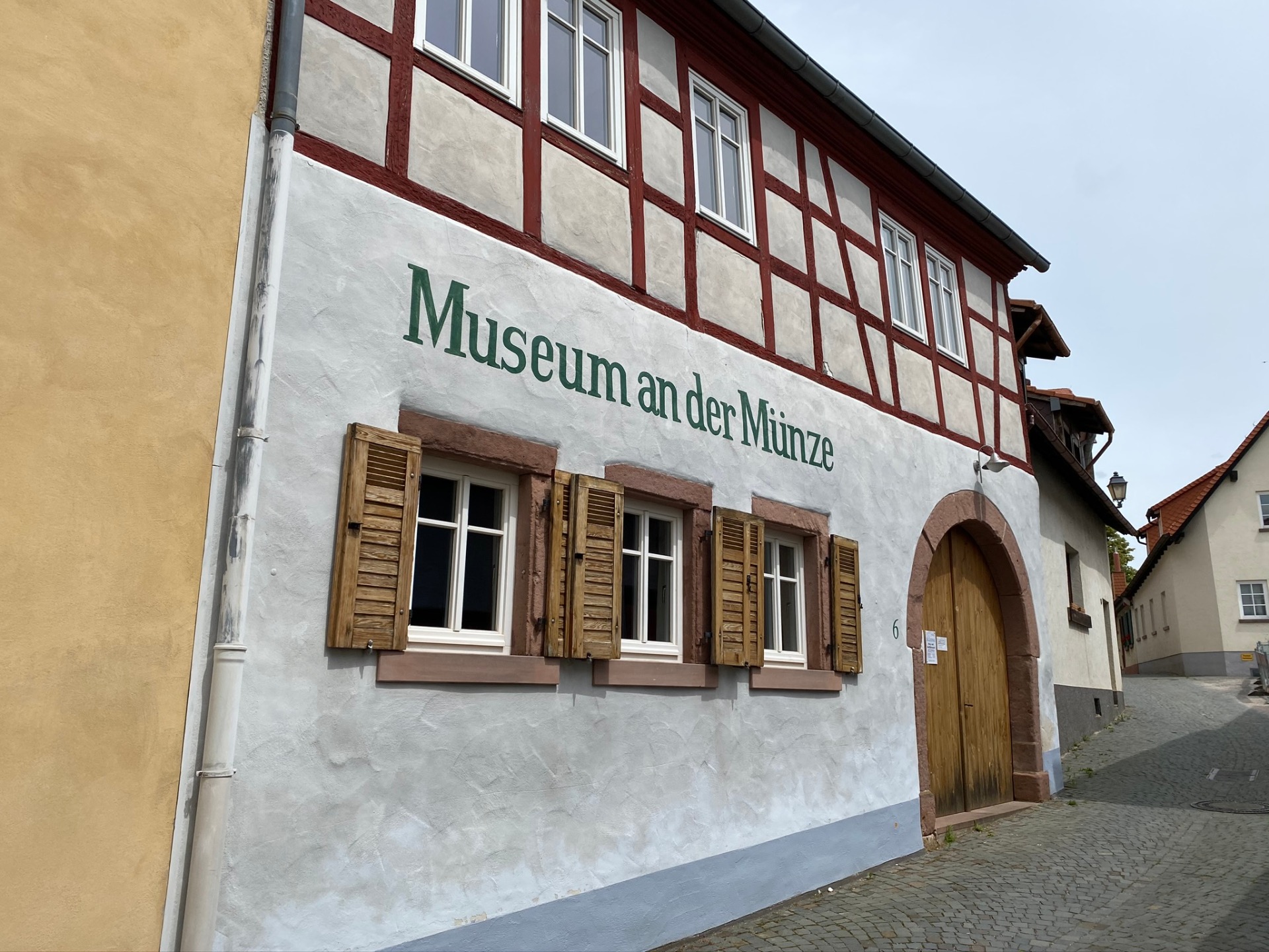 Fachwerkhaus mit weißen Wänden, braunen Fensterläden und grünem Schriftzug 'Museum an der Münze' über drei Fenstern.